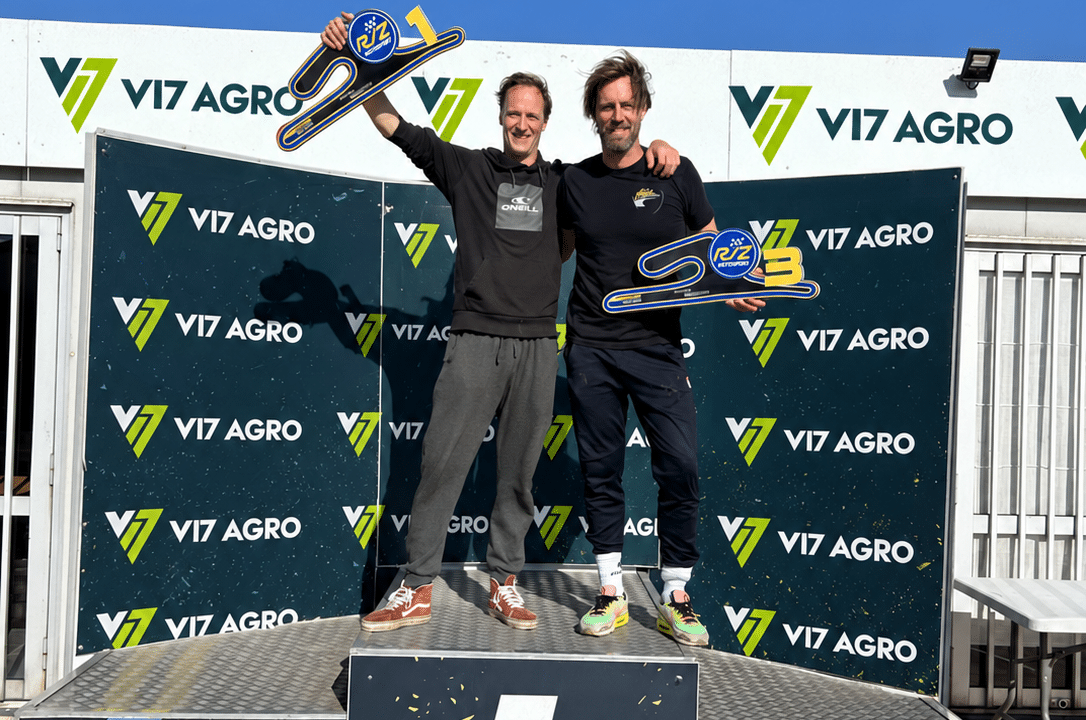Twee mannen met trofeeën op een erepodium, met V17 Agro-logo’s op de achtergrond.